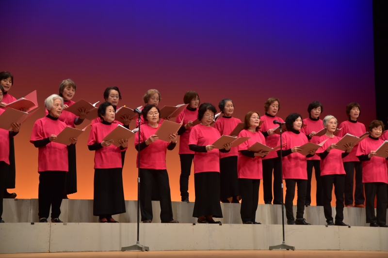 フィナーレの写真、お揃いの赤いTシャツを着て歌う婦人たちの写真
