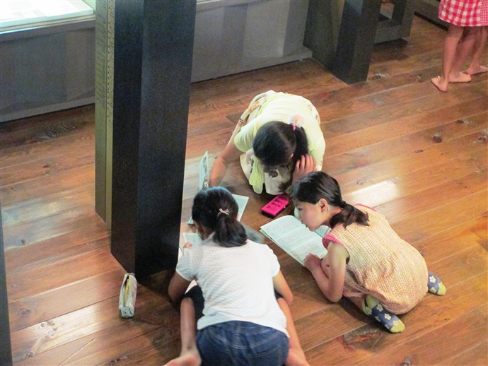 資料館見学にて、3人の子どもがノートに記述している様子の写真